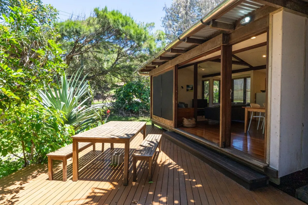 Wide doors folded open from a house onto a timber deck with a garden table