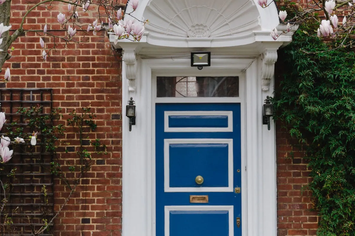 Blue panelled front door with a white surround on a red brick house